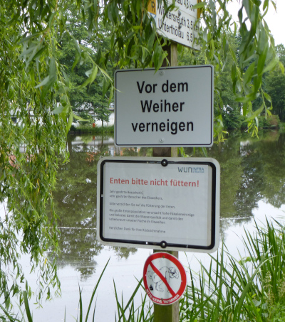 Schild mit folgender Anweisung: Vor dem Weiher verneigen.